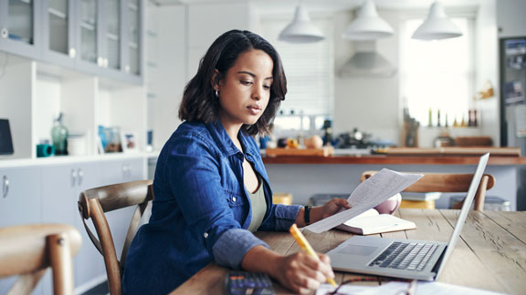 Woman Working on Laptop and Making Notes